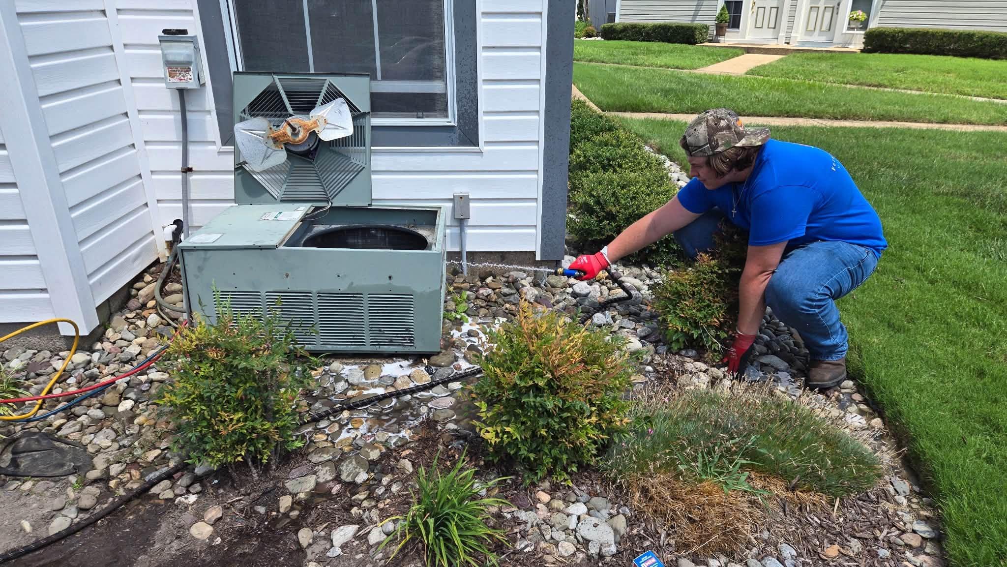 Ferguson & Sons technician cleaning a residential outdoor HVAC unit