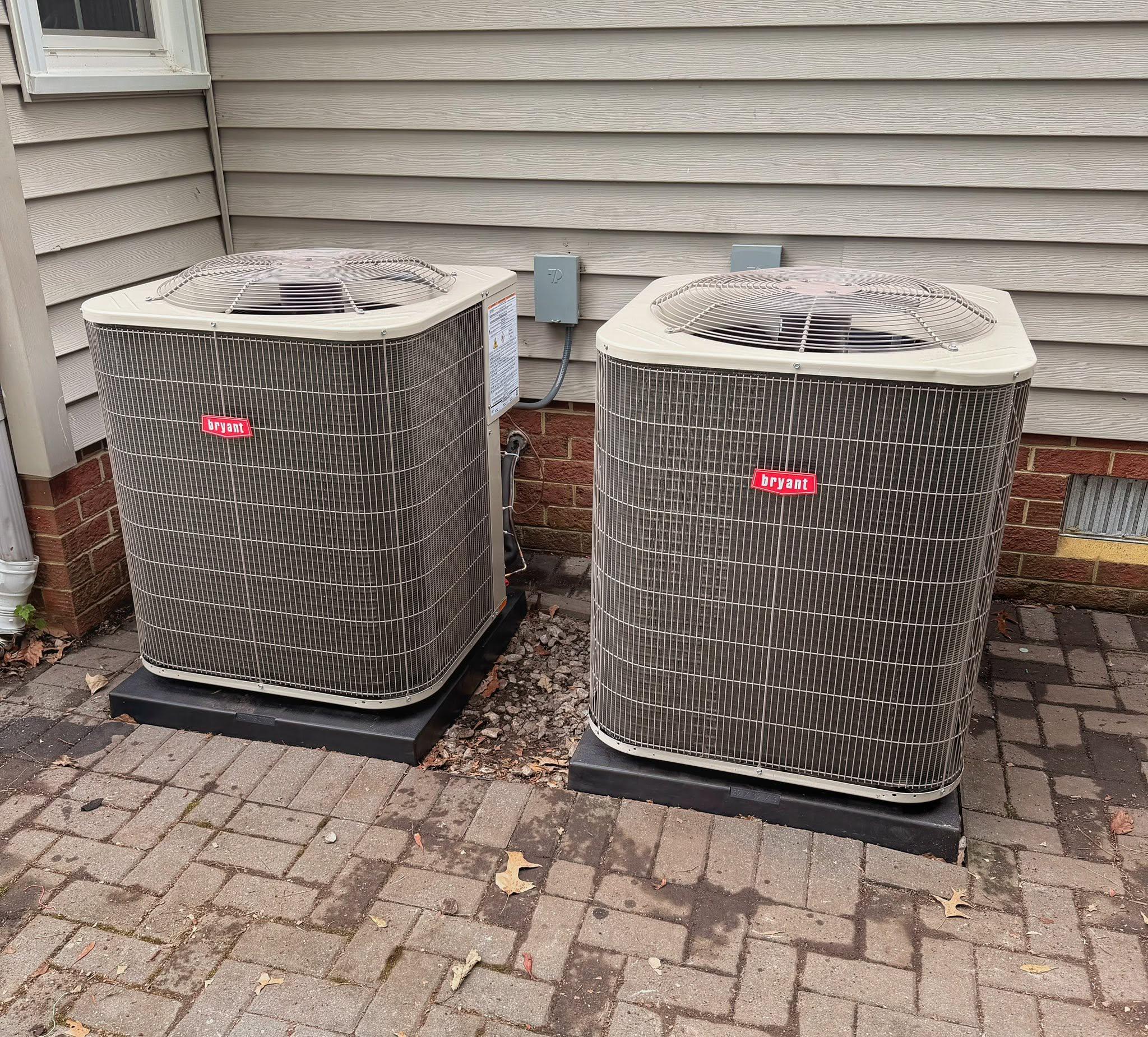Two residential outdoor HVAC systems installed beside a home