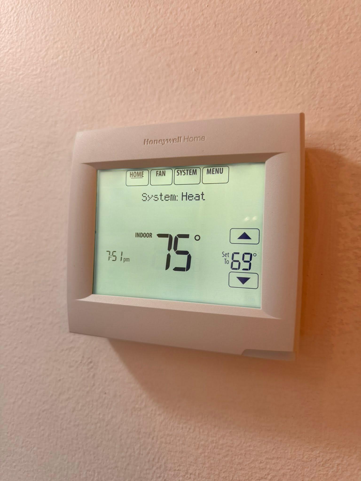 Wall-mounted thermostat displaying heating settings