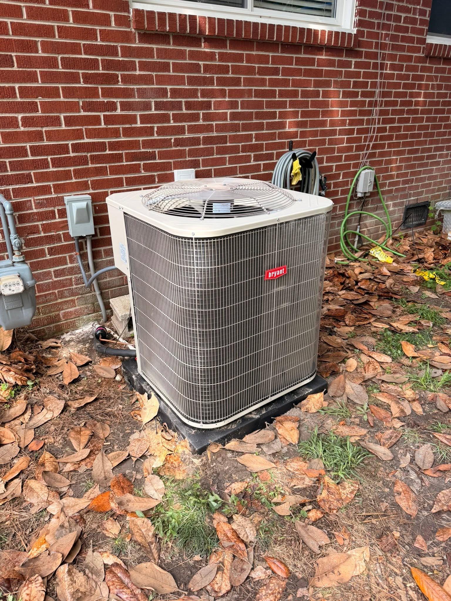 New residential outdoor HVAC system installed beside a brick home