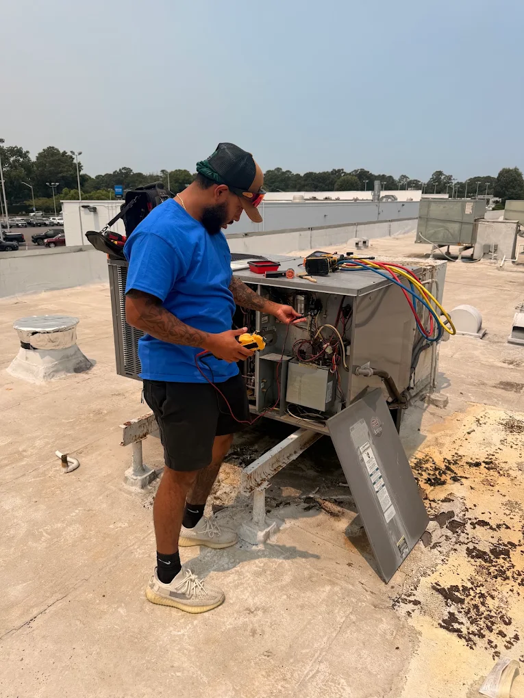 Technician diagnosing a commercial rooftop HVAC unit