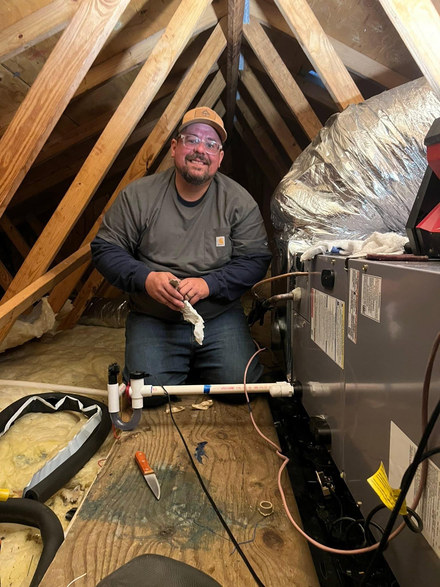 Technician servicing HVAC equipment in an attic